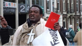 Manifestant qui brandit le livre Code Noir et le calvaire de Canaan.