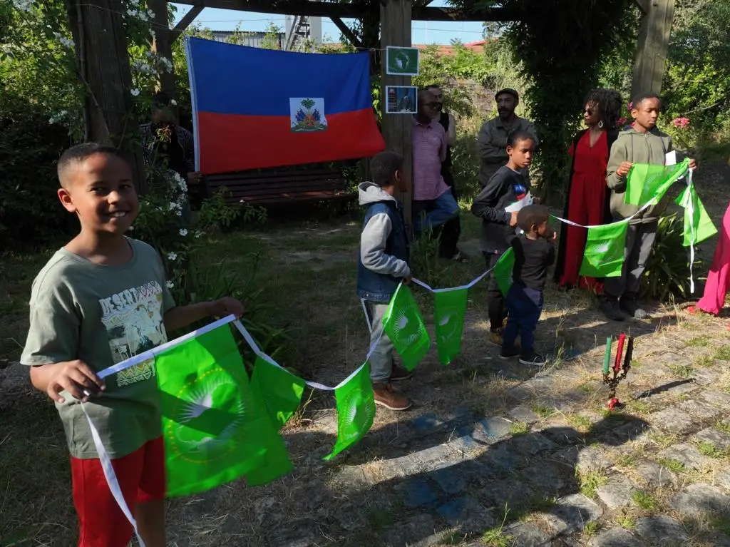 Plan rapproché sur les drapeaux haïtien et panafricain portés par les enfants au square Toussaint Louverture-Nantes.